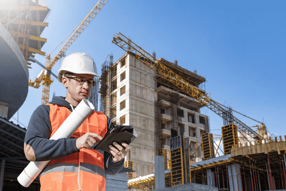 two construction workers looking over a project plan while on a busy worksite